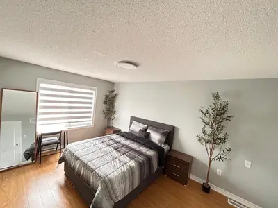 a bedroom with a bed and a table and a window at Luxury home Netflix & parking promo price with 7beds in Brampton