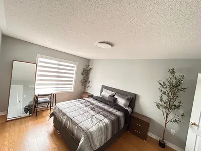 a bedroom with a bed and a window and a chair at Luxury home Netflix & parking promo price with 7beds in Brampton