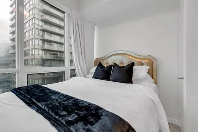 a bedroom with a bed with a large window at Luxe 3-Bedroom Lakeview Condo, Free parking ,Walk to CN Tower, Scotiabank Arena & Rogers Centre in Toronto