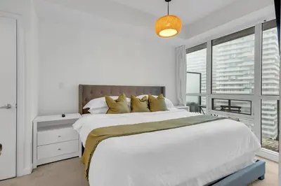 a white bedroom with a large bed and a window at Luxe 3-Bedroom Lakeview Condo, Free parking ,Walk to CN Tower, Scotiabank Arena & Rogers Centre in Toronto