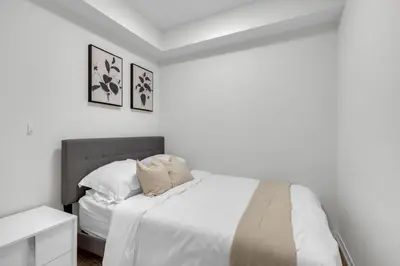 a white bedroom with a bed with white sheets and pillows at Luxe 3-Bedroom Lakeview Condo, Free parking ,Walk to CN Tower, Scotiabank Arena & Rogers Centre in Toronto