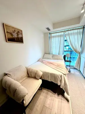 a bedroom with a bed and a couch and a window at Cozy studio near Yonge Eglinton Subway Midtown in Toronto