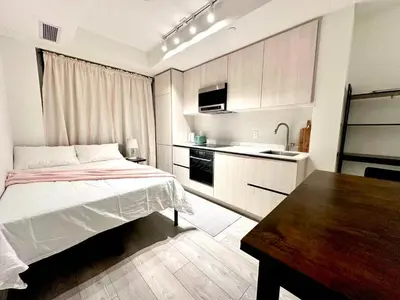 a small bedroom with a bed and a kitchen at Cozy studio near Yonge Eglinton Subway Midtown in Toronto