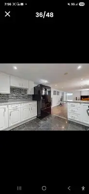 a kitchen with white cabinets and a black counter top at Cozy home in Toronto