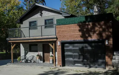 a house with a large garage with a balcony at Evergreen Escape - 3 Acres, Hot Tub, Volleyball Court in Collingwood