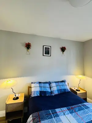a bedroom with a blue bed and two tables with lamps at Cozy Place in Oshawa