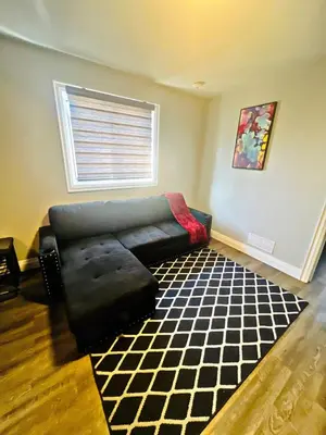 a living room with a black couch and a window at Cozy Place in Oshawa