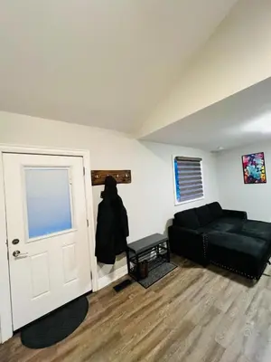 a living room with a black couch and a door at Cozy Place in Oshawa