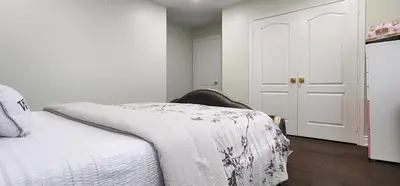 a bedroom with a bed with a white blanket on it at Charming Room in Brampton