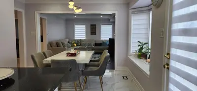 a dining room and living room with a table and chairs at Lavish Bright Bedroom in Brampton