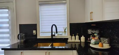 a kitchen with a sink and a black counter top at Lavish Bright Bedroom in Brampton