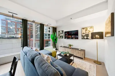 a living room with a blue couch and a large window at Spacious Condo with 2 Beds Unbeatable Location in Toronto