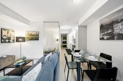 a living room with a blue couch and a table at Spacious Condo with 2 Beds Unbeatable Location in Toronto