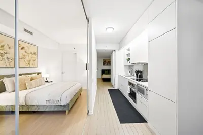 a white bedroom with a bed and a kitchen at Spacious Condo with 2 Beds Unbeatable Location in Toronto