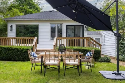 a table with chairs and an umbrella in front of a house at New Modern Home in Old Town in Niagara on the Lake