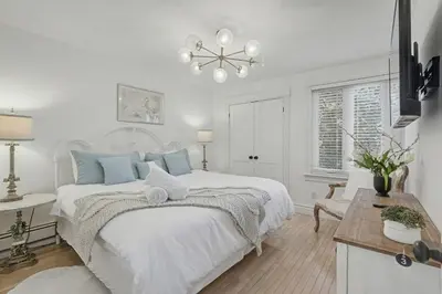a white bedroom with a bed and a table at Upscale Modern Home with Spa Pool in Niagara on the Lake