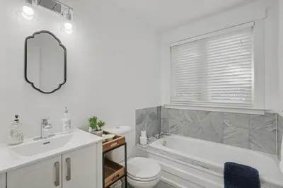 a bathroom with a tub and a toilet and a sink at Upscale Modern Home with Spa Pool in Niagara on the Lake