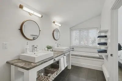 a white bathroom with a sink and a mirror at Upscale Modern Home with Spa Pool in Niagara on the Lake