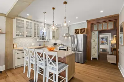 a kitchen with white cabinets and a island with bar stools at Modern French Cottage in Old Town The 506 in Niagara on the Lake