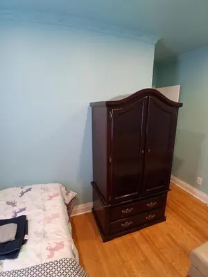 a bedroom with a large wooden cabinet next to a bed at Greenhills - 3 bedroom suit - main floor in Toronto