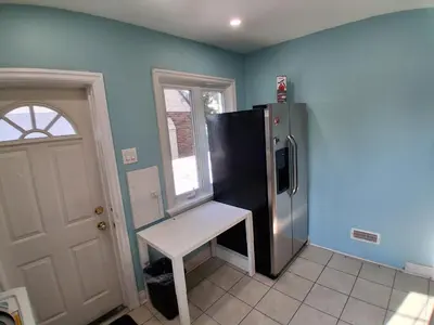 a kitchen with a black refrigerator and a white stool at Greenhills - 3 bedroom suit - main floor in Toronto