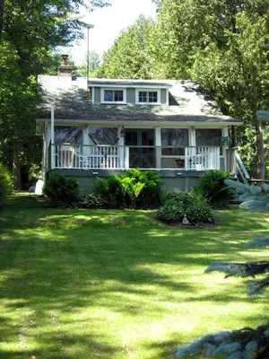 a house on a lawn with trees andgrass at Waterfront Muskoka Cottage on Trent-Severn River in Severn