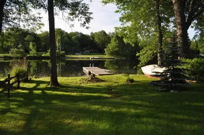 a park with a bench and a boat in the grass at Waterfront Muskoka Cottage on Trent-Severn River in Severn