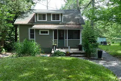 a small green house with a porch and a yard at Waterfront Muskoka Cottage on Trent-Severn River in Severn