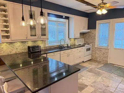 a kitchen with white cabinets and a black counter top at Private Lakehouse Getaway Hot Tub on the Water in Waubaushene