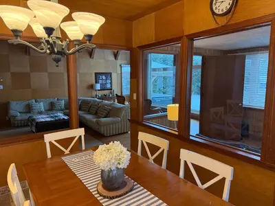 a living room with a dining room table with a clock at Private Lakehouse Getaway Hot Tub on the Water in Waubaushene