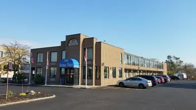 a building with a clock on it in a parking lot at Avenue Motel in Mississauga