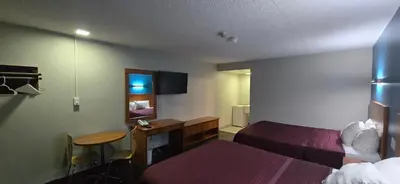 a hotel room with two beds and a desk at Avenue Motel in Mississauga