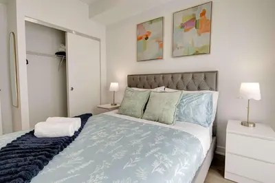 a bedroom with a blue and white bed with two lamps at Modern High-Rise Condo w City Views & Balcony in Kitchener