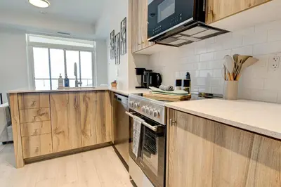 a kitchen with wooden cabinets and a stove top oven at Modern High-Rise Condo w City Views & Balcony in Kitchener