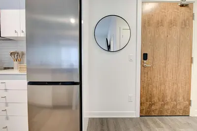 a refrigerator in a kitchen with a mirror on the wall at Stylish Downtown Suite with Patio & City Views in Kitchener