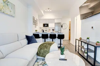 a living room with a white couch and a kitchen at Stylish Downtown Suite with Patio & City Views in Kitchener