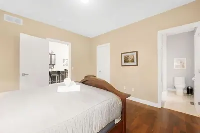 a bedroom with a white bed and a bathroom at Beautiful 3BR Old Town Home Steps to Queen St in Niagara on the Lake
