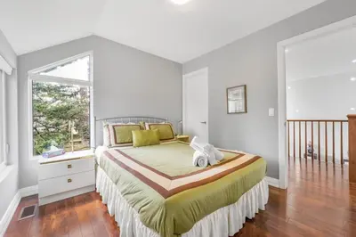 a bedroom with a large bed and a window at Beautiful 3BR Old Town Home Steps to Queen St in Niagara on the Lake
