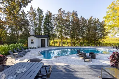 a swimming pool with chairs and a table at Vineyard Estate by the River with Pool in Niagara on the Lake