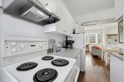 a white kitchen with a white stove top oven at 1 Bed Suite Steps to Bloor in Toronto