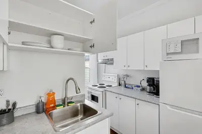a white kitchen with a sink and a refrigerator at 1 Bed Suite Steps to Bloor in Toronto