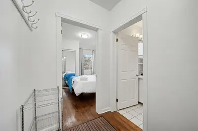 a white room with a bed and a mirror at 1 Bed Suite Steps to Bloor in Toronto