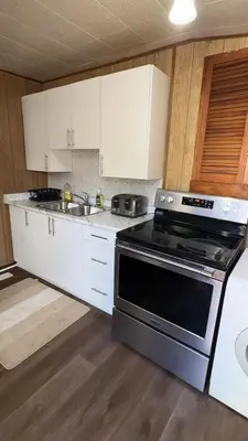 a kitchen with a stove and a sink and white cabinets at Cozy 3BR House Near Airport & Transit! in Mississauga