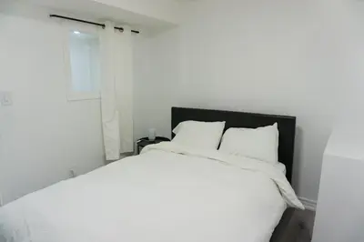 a white bed with white sheets and a window at Modern 3 Bedroom Guest Suite in Toronto