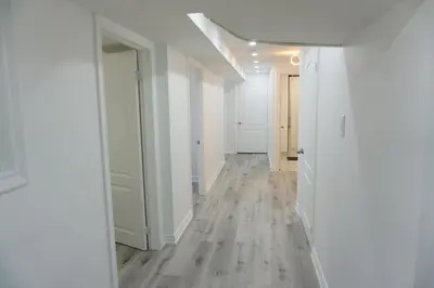 an empty hallway with white walls and wood floors at Modern 3 Bedroom Guest Suite in Toronto