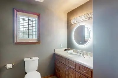 a bathroom with a toilet and a sink and a mirror at Main House in Wasaga Beach