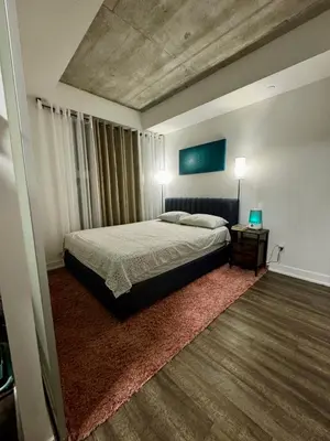 a bedroom with a bed and a table with two lamps at Condo in the heart of toronto in Toronto