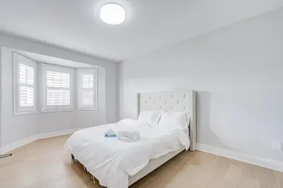 a white bedroom with a large bed with white sheets at Vantage stay Stouffville 4BR Bright Home in Stouffville