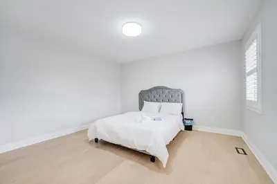a white bedroom with a bed with a gray headboard at Vantage stay Stouffville 4BR Bright Home in Stouffville