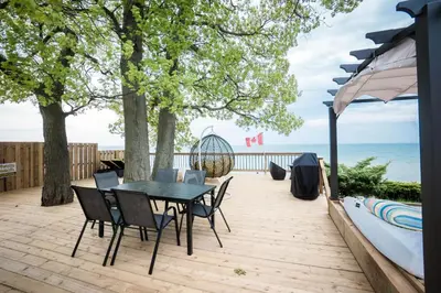 a patio with a table and chairs and the ocean at Beach Front Family Cottage Ping Pong & Karaoke in Fort Erie